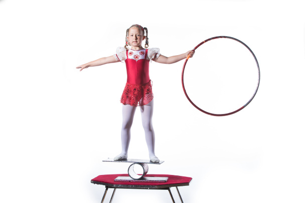 Petite fille équilibrage acte sur fond blanc. Jeune gymnaste équilibrage actrice avec le cerceau
 - Photo, image