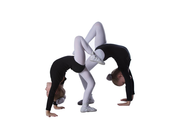 Girls gymnasts on a white background. Two little acrobats perform a number - Photo, Image
