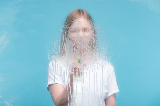selective focus of young woman cleaning glass with dripping detergent on blue background - Foto, Bild