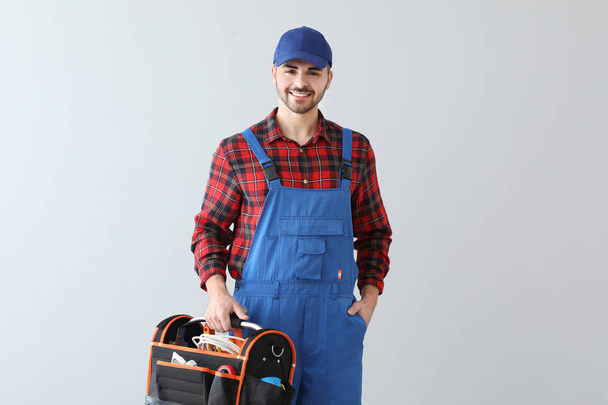 eletricista masculino com kit de ferramentas em fundo claro
 - Foto, Imagem