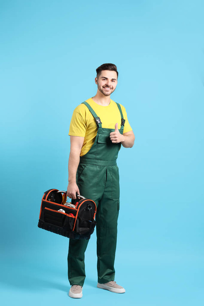 Male electrician with tools kit on color background - Фото, изображение