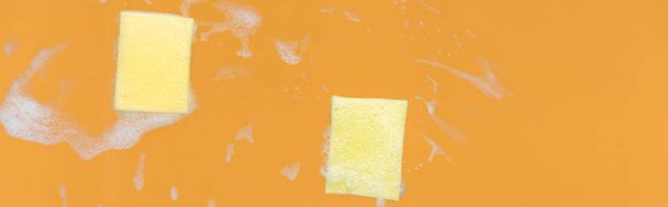 panoramic shot of of yellow sponges with foam on orange background - Foto, afbeelding
