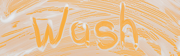 Panoramaaufnahme von Glas mit weißem Schaumstoff auf orangefarbenem Hintergrund mit Wash-Schriftzug - Foto, Bild
