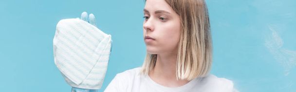 panoramic shot of young woman in rubber glove cleaning glass with rag on blue background - Foto, imagen