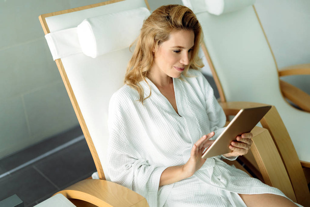 Mooie vrouw ontspannen en het gebruik van digitale tablet in spa - Foto, afbeelding