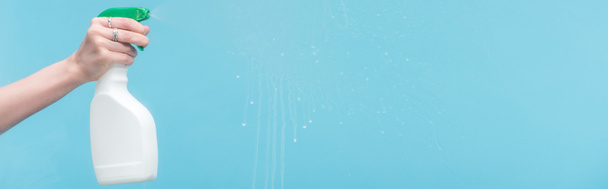 plan panoramique de femme pulvérisation de verre avec détergent sur fond bleu
 - Photo, image