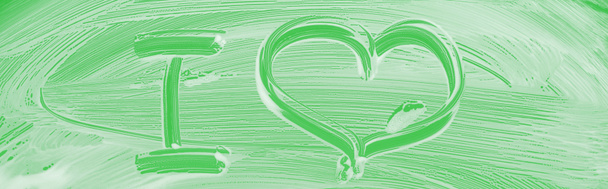 panoramic shot of glass covered with white foam on green background with I letter and heart sign - Photo, Image