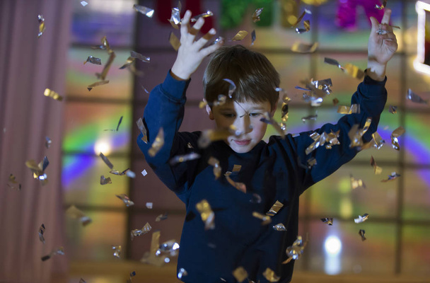 Gyermek dob csillogó konfetti. Esőben ezüstszínű fiú - Fotó, kép