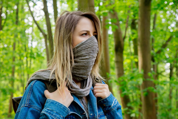 woman with backpack hide face with a scarf in forest  - Фото, изображение