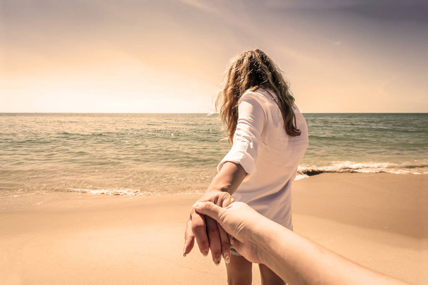 Vue arrière d'un couple faisant une promenade en se tenant la main sur la plage, effet sépia
 - Photo, image