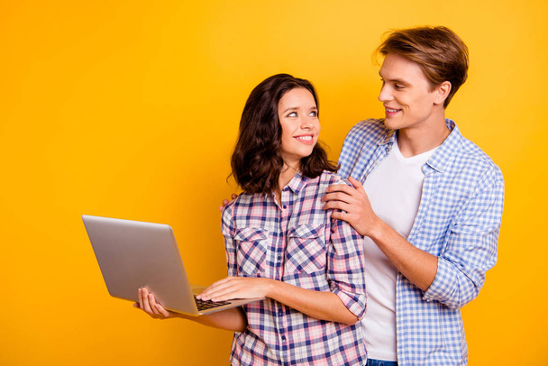 Close up photo of pair in love he him his she her lady boy with computer in hands best intentions looking for web network wearing casual plaid shirts outfit isolated on yellow background - 写真・画像