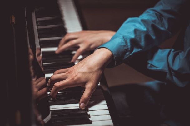 two male hands on the piano. palms lie on the keys crosswise and play the keyboard instrument in the music school. student learns to play. hands pianist. black dark background. top view - Photo, Image
