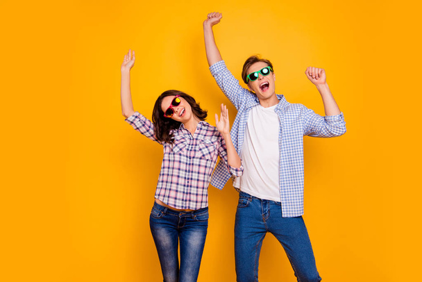 Close up photo of pair in summer specs he him his she her lady boy hands up dancing yelling cheer great bit luck wearing casual plaid shirts outfit isolated on yellow background - 写真・画像