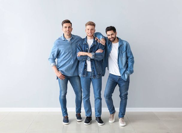 Homens jovens na moda perto da parede leve
 - Foto, Imagem
