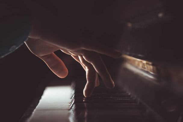 one male hand on the piano. The palm lies on the keys and plays the keyboard instrument in the music school. student learns to play. hands pianist. black dark background - Foto, afbeelding