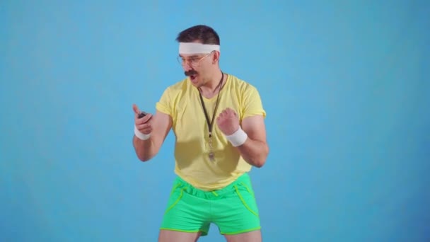 Funny joyful male trainer from the 80s with a mustache and glasses with a stopwatch - Séquence, vidéo