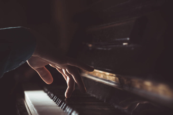 one male hand on the piano. The palm lies on the keys and plays the keyboard instrument in the music school. student learns to play. hands pianist. black dark background - 写真・画像