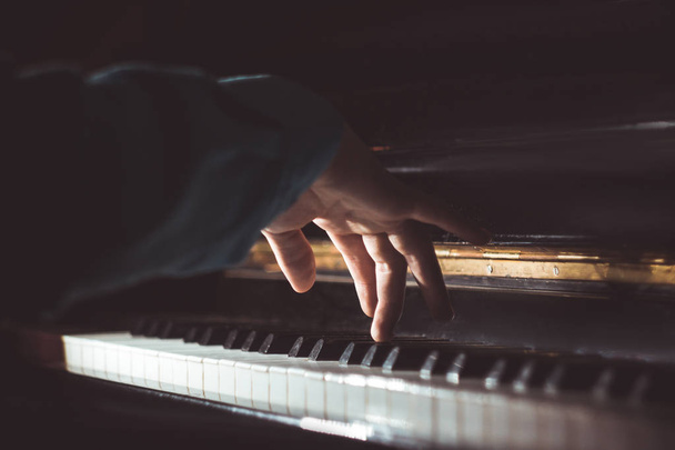 one male hand on the piano. The palm lies on the keys and plays the keyboard instrument in the music school. student learns to play. hands pianist. black dark background - Fotó, kép