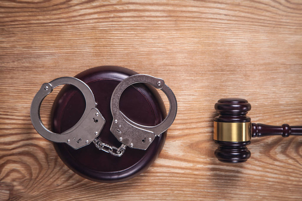 Metal handcuffs and judge gavel on wooden background. Crime and  - Zdjęcie, obraz