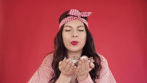 Pretty girl with headband blowing confetti at camera. - Filmati, video
