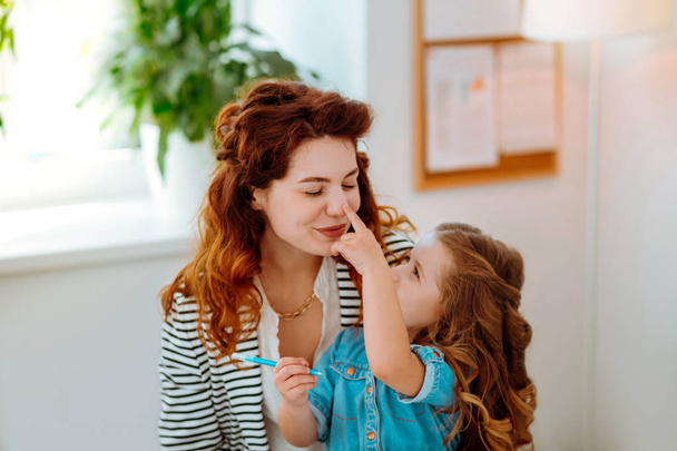 Lovely daughter touching nose of her loving young mother - Φωτογραφία, εικόνα
