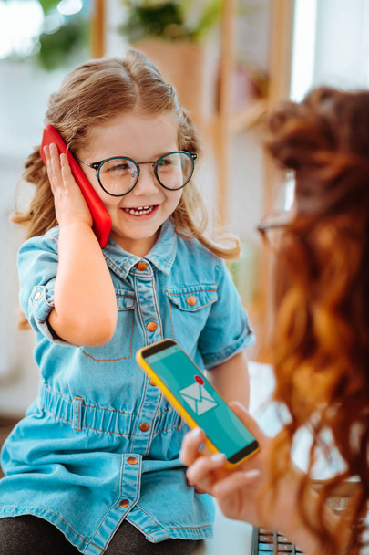 Cheerful daughter calling dad while visiting mom at work - Fotoğraf, Görsel
