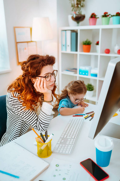 Mom working remotely having many tasks while sitting near daughter - Fotoğraf, Görsel