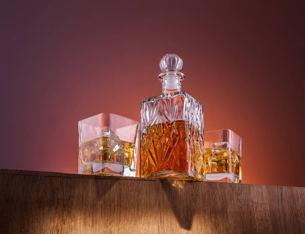 Alkol ile eski moda cam ve carafe, sıcak viski içecek, koyu turuncu arka plan ve ahşap - Fotoğraf, Görsel