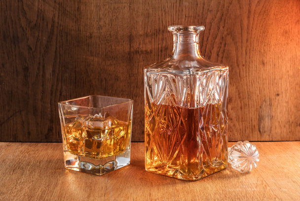 Old fashion glass and carafe with the alcohol, whisky drink on warm wood background  - Photo, image