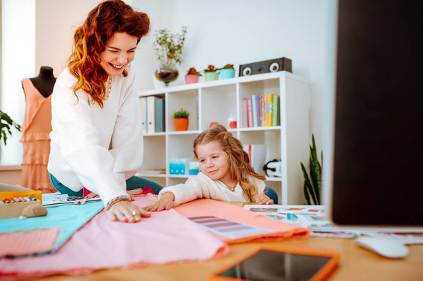 Mother laughing while her daughter helping her designing clothes - Foto, Bild