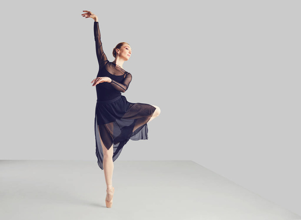 Ballerina in a black tutu elegantly dancing on a black background. - Valokuva, kuva