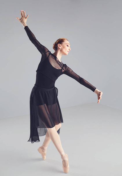 Ballerina in a black tutu elegantly dancing on a black background. - Fotoğraf, Görsel