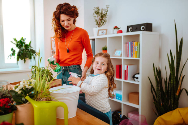 Mother and daughter using diffusers watering home plants - 写真・画像