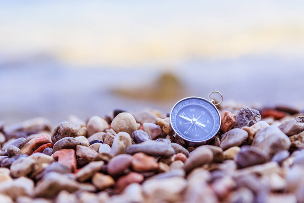Navigation concept: Compass is lying on the beach near the sea - Foto, afbeelding