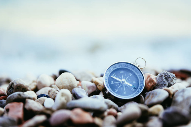 Navigation concept: Compass is lying on the beach near the sea - Foto, afbeelding