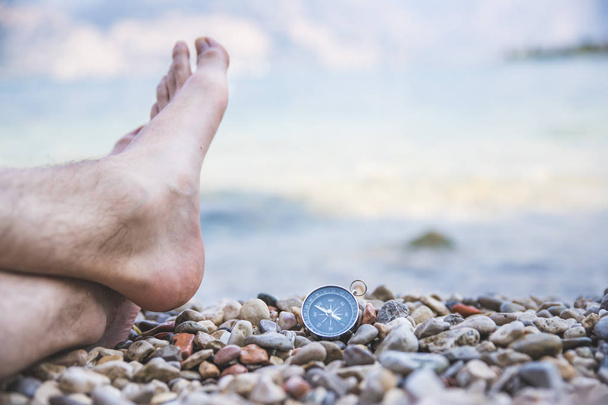 World travel concept: Male feet and compass on the beach near th - Zdjęcie, obraz