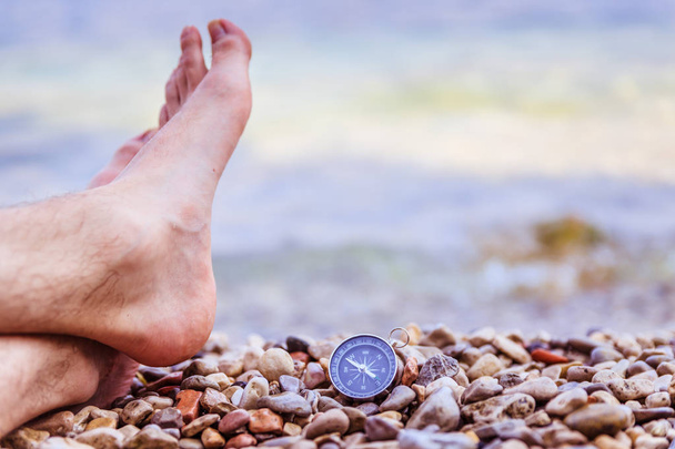 World travel concept: Male feet and compass on the beach near th - Foto, Bild