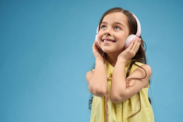 Little girl listening music in pink headphones. - Foto, imagen