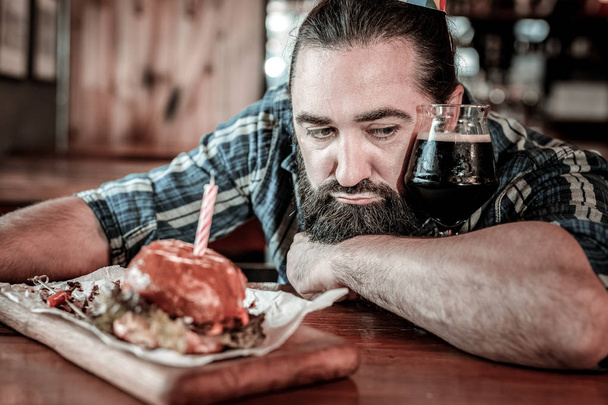 Grumpy bearded man resting his head on a pub table. - Фото, зображення