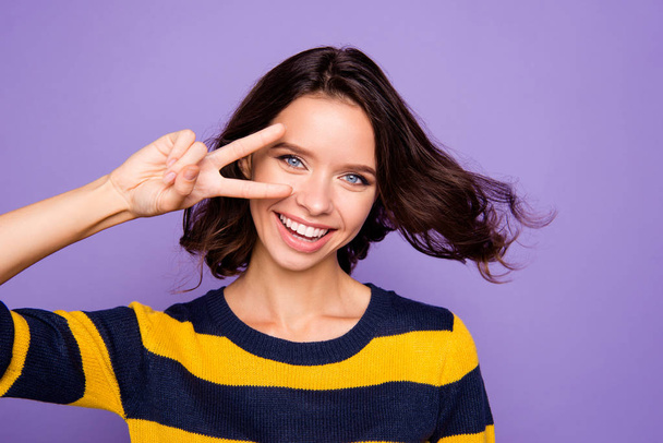 Close up photo beautiful amazing funky she her lady hand arm v-sign near eye enjoy warm wind pretty overjoyed hairstyle flight wear blue yellow striped pullover isolated violet purple background - Fotografie, Obrázek