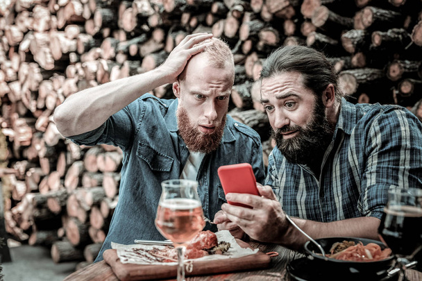 Two men being surprised at news they seeing on a smartphone. - Zdjęcie, obraz