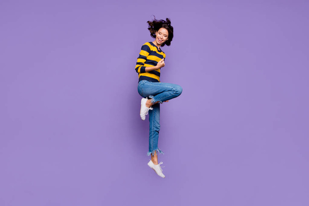 Full length body size side profile photo beautiful she her lady hands arms fists air yell scream shout jump high flight playful mood wear blue yellow striped pullover isolated violet purple background - Photo, image