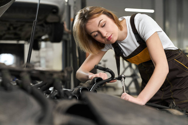 Pretty girl mechanic in uniform repairing, fixing car. - Fotó, kép