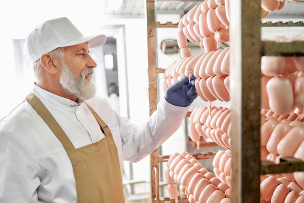 Meat factory production worker observing sausages. - Fotoğraf, Görsel