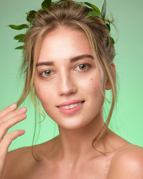 Beauty portrait of woman face with freckles wears a crown of green leaves. - Foto, afbeelding