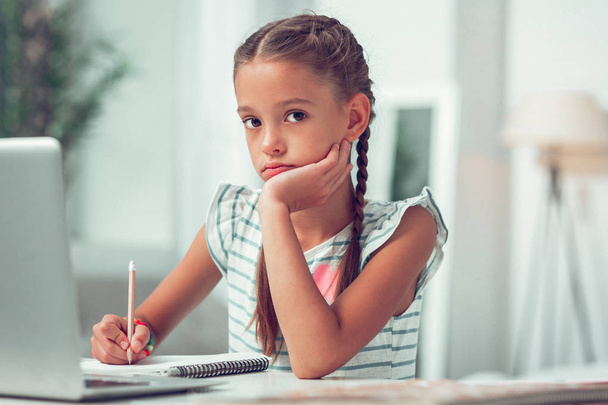Close-up portrait photo of Afro-American lovely little schoolkid doing homework. - 写真・画像