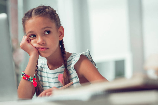 Face portrait of Afro-American schoolchild spending time doing boring homework. - Photo, image