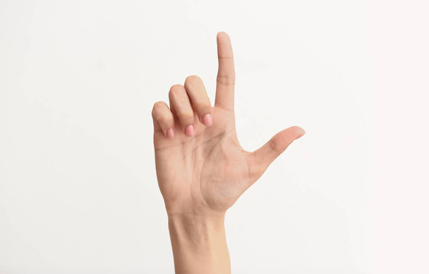 weibliche Hand zeigt Buchstaben l auf hellem Hintergrund - Foto, Bild