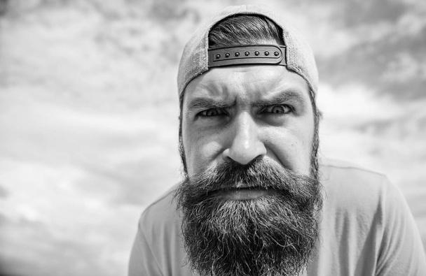 Staring straight before him. Brutal man with long beard and serious look. Bearded man in fashion hipster cap outdoor. Hipster in street fashion wear on cloudy sky. Cool hipster - Foto, Imagen
