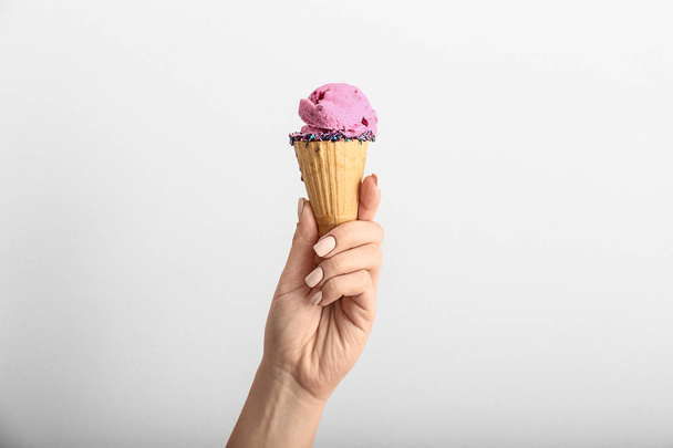 Mano femenina con sabroso helado sobre fondo claro
 - Foto, imagen